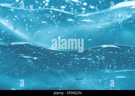 Un'immagine macro in primo piano di un gel blu traslucido con texture intricate e numerose bolle. La superficie mostra un motivo fluido e ondulato, catturando Foto Stock