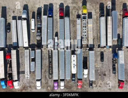 Camion e rimorchi parcheggiati in un grande parcheggio logistico e di distribuzione visti dall'alto Foto Stock