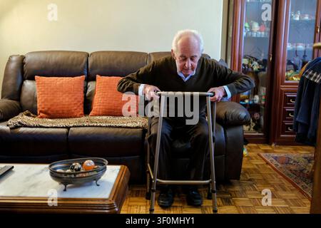 Uomo anziano che utilizza un bastone da passeggio per supporto a casa, concentrandosi sulla mobilità e l'indipendenza Foto Stock