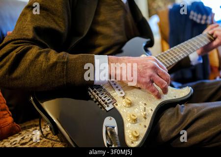Anziano che suona la chitarra elettrica, godendosi il suo hobby musicale e il tempo libero Foto Stock