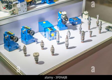 Una esposizione di valvole solenoide idrauliche industriali blu, collettori di controllo della pressione e valvole a cartuccia in acciaio inossidabile per macchine pesanti e automobili Foto Stock