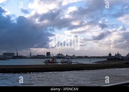 Vista dalla nave traghetto TESO di un porto marittimo con gru, navi, un molo e edifici sul lungomare nella zona del Mare di Wadden e Marsdiep vicino a Texel, Nord Foto Stock