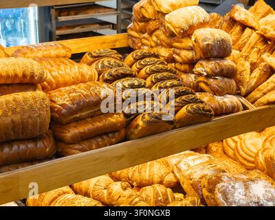 Varie assortimento di panini dolci e pane croccante impilati ordinatamente in una vetrina del negozio, che illustra la qualità culinaria e la selezione gourmet per un t accogliente Foto Stock