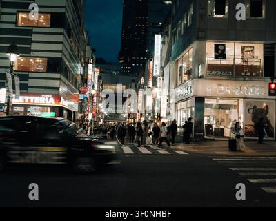Via notturna con insegne al neon, pedoni che attraversano e un taxi di passaggio a Dogenzaka, Shibuya, Tokyo, Giappone Foto Stock