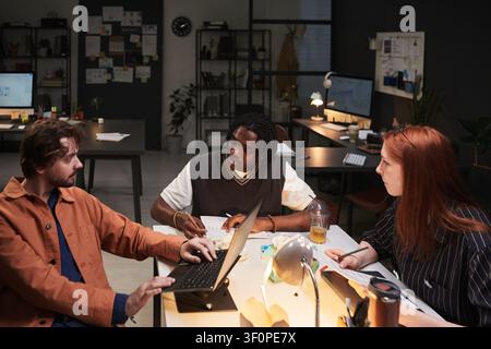 Diversi colleghi che collaborano durante una riunione in ufficio a tarda notte Foto Stock