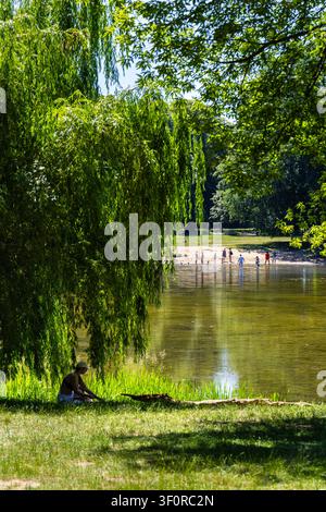 Persone che si rilassano vicino a uno stagno nel parco Skaryszewski in una calda giornata estiva, Saska Kepa, Varsavia, Polonia Foto Stock