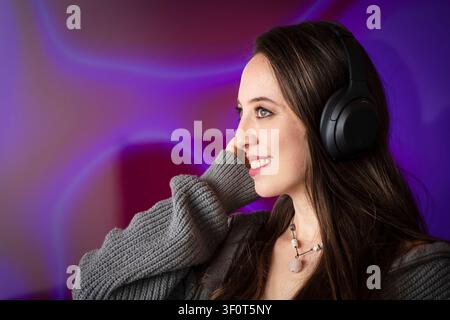 Giovane donna che si gode la musica con cuffie wireless Foto Stock