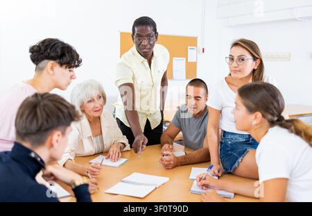 Gruppo multirazziale di età mista partecipante classe di istruzione per adulti con tutor afro-americano Foto Stock