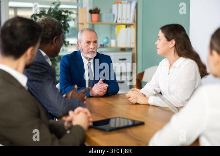 Gruppo di uomini d'affari e donne d'affari che tengono una riunione al tavolo Foto Stock