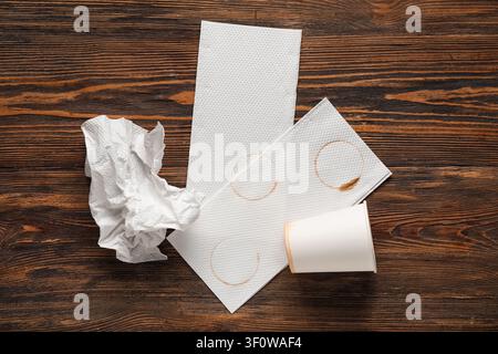 Bicchiere di carta e tovaglioli con macchie di caffè su sfondo di legno Foto Stock
