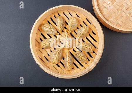 Vista dall'alto di ravioli coreani di kimchi Mandu cotti a vapore in un cestino tradizionale di bambù Foto Stock