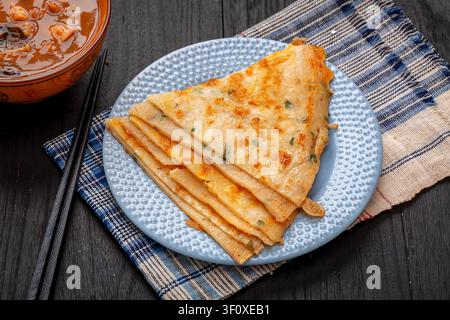 Tradizionali pancake cinesi croccanti alle cipolle verdi serviti su piatto blu, pane azzimo saporito alla cipolla verde Foto Stock