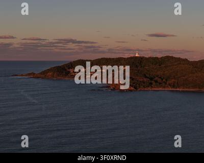 Vista aerea del faro di Byron Bay sulla penisola al tramonto con l'oceano e la costa a Byron Bay, Nuovo Galles del Sud, Australia. Foto Stock