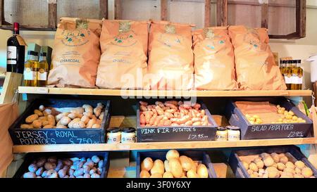Esposizione di un negozio agricolo con patate Jersey Royal e Pink Fir e carbone sugli scaffali Foto Stock