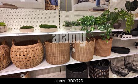 Vista interna di oggetti per l'arredamento domestico esposti su scaffali in un grande magazzino, con cesti in vimini intrecciati e piante artificiali Foto Stock