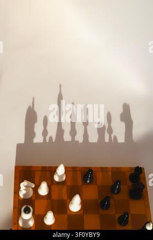 Un piano verticale a flat lay e una ripresa dall'alto di una scacchiera di legno con pezzi neri e bianchi disposti per giocare. Foto Stock