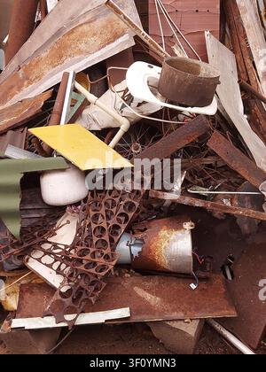 Cumulo di rottami arrugginiti con fogli di acciaio scartati, tubi, filo, oggetti domestici e rifiuti industriali in un centro di riciclaggio. Concetto di riciclaggio dei metalli, gestione dei rifiuti, inquinamento ambientale, ind. Foto Stock