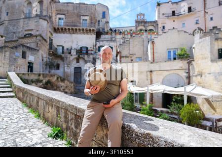 Visitatore maschio che si rilassa nel famoso distretto di pietra di Matera, circondato da architettura secolare e panorami urbani scenografici Foto Stock
