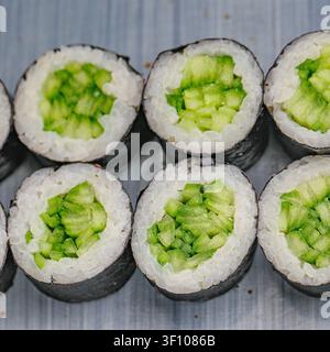Una varietà di rotoli di sushi, con diversi tipi e condimenti, disposti ordinatamente su un tavolo. Foto Stock