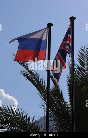 La bandiera russa sventola al vento e la bandiera britannica pende immobile nelle vicinanze. Orientamento verticale della foto. Foto Stock
