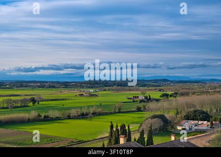 Campi verdi, fattorie e colline lontane sotto un bellissimo cielo serale in una giornata invernale soleggiata. Vicino alla città di Pals, Girona, Catalogna, Spagna Foto Stock