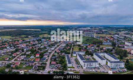 Vista panoramica aerea di un quartiere residenziale moderno al tramonto sotto un cielo nuvoloso drammatico Foto Stock