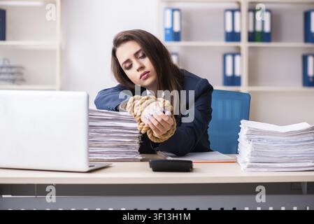 Giovane bella dipendente legato con corda in ufficio Foto Stock