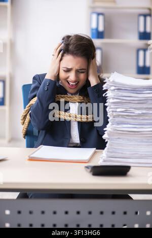 Giovane bella dipendente legato con corda in ufficio Foto Stock