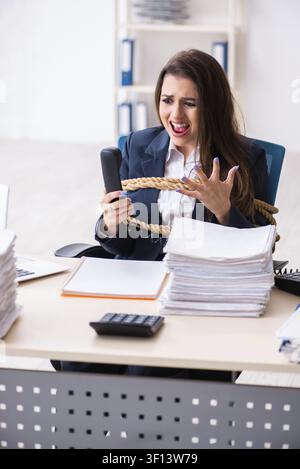 Giovane bella dipendente legato con corda in ufficio Foto Stock