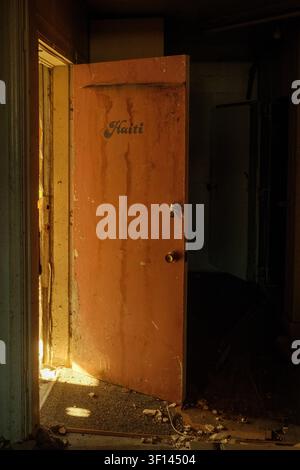 La luce del sole illumina una porta aperta all'interno di un edificio commerciale abbandonato a Green River, Utah, USA. Foto Stock