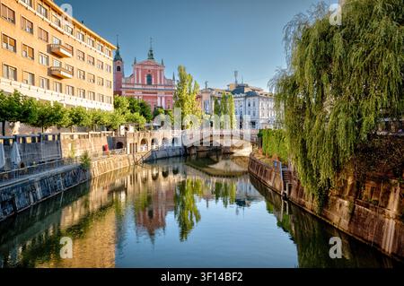 Il fiume Ljubljanica, il Ponte Triplo e la Chiesa Francescana dell'Annunciazione si riflettono nell'acqua calma a Lubiana, in Slovenia. Foto Stock