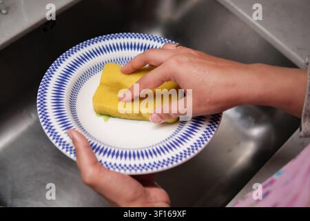 Lavare i piatti con cura al lavandino della cucina Foto Stock