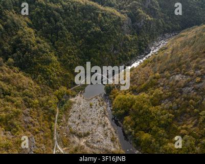 Vista aerea del Ponte del Diavolo che si estende sul fiume Arda, circondato da fitte foreste autunnali e pendici rocciose nella provincia di Kardzhali, in Bulgaria. Foto Stock