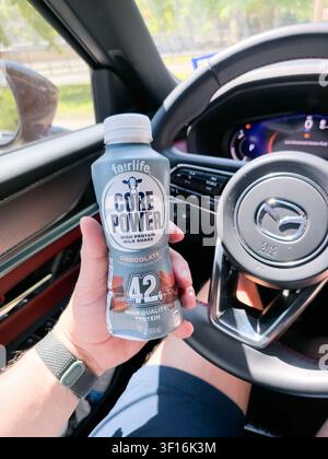Una persona tiene una bottiglia di frullato al cioccolato ad alto contenuto proteico Core Power all'interno di un veicolo Mazda. Core Power, prodotto da fairlife, è noto per il suo alto Foto Stock