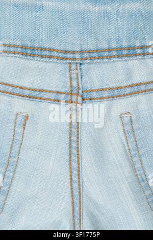 Vista dettagliata di denim azzurro con trama visibile che contrasta con le cuciture marroni. Focus sulle cuciture delle tasche e la costruzione della cintura. Materiale naturale morbido Foto Stock