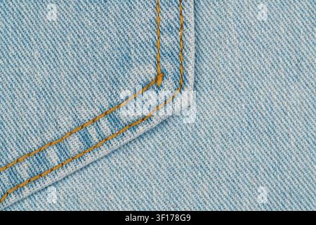 Denim blu chiaro strutturato con cuciture dorate agli angoli delle cuciture. Vista macro evidenzia il contrasto del motivo della trama. Ideale per moda, tessile, casua Foto Stock