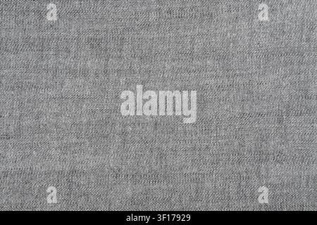 Primo piano di tessuto denim grigio che mostra una trama diagonale dettagliata. Tonalità neutre con sottili variazioni di sfumatura. Ideale per sfondo, design, te Foto Stock
