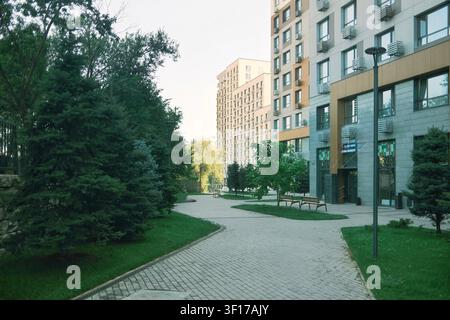 Bellissimo cortile paesaggistico tra moderni edifici residenziali con percorsi pedonali, alberi e spazi verdi in un quartiere contemporaneo Foto Stock