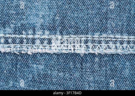 Texture di tessuto di jeans blu rovesciato con dettagli di cuciture pesanti. Primo piano di un motivo tessile in cotone sbiadito. Costruzione industriale di abiti, c Foto Stock