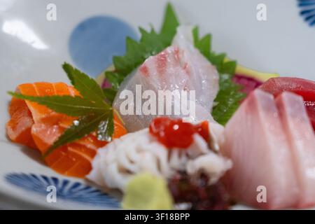 Un piatto elegante di autentico sashimi giapponese con fette premium di salmone crudo, tonno, hamachi e pesce bianco, splendidamente disposto con fresco Foto Stock
