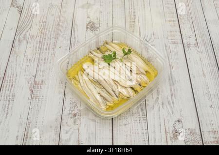 Filetti di acciughe bianche marinati in olio d'oliva con guarnizione di prezzemolo fresco in contenitore di plastica trasparente Foto Stock