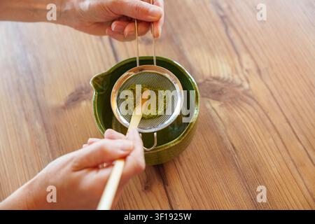 Setacciando la polvere di matcha in una ciotola per una ricetta di latte freddo fatto in casa Foto Stock