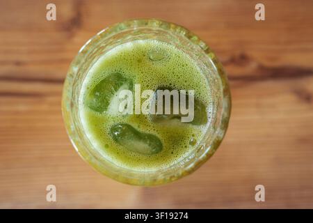 Vista dall'alto di un latte freddo al mango e matcha con ghiaccio su un tavolo di legno Foto Stock