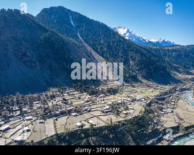 Vista aerea della foresta di Ushu e del villaggio di Kalam con campi terrazzati, un fiume sinuoso e montagne innevate a Kalam, Khyber Pakhtunkhwa, Pakistan Foto Stock