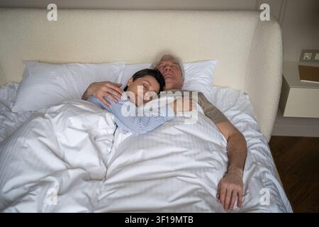 Coppia sposata anziana felice e rilassata, moglie e marito che dormono tranquillamente a letto e si abbracciano. Foto Stock