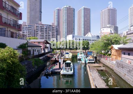 Canale storico di Tokyo, Giappone, fiancheggiato da case tradizionali per barche e moderni grattacieli residenziali a Tsukishima Foto Stock