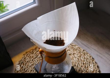 Prima vista dell'acqua calda che fuoriesce da un bollitore in una caffettiera in vetro Chemex per la preparazione manuale Foto Stock