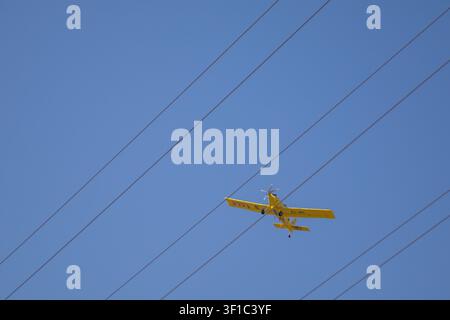 Aereo antincendio Air Tractor gestito dalla Generalitat de Catalunya che vola sotto un cielo blu terso con linee ad alta tensione che attraversano il Foto Stock