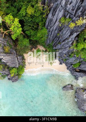 Vista aerea di una coppia sdraiata sulla sabbia in posizione a stella su una spiaggia di Shimizu Island, circondata da scogliere di calcare e acqua turchese a El Foto Stock