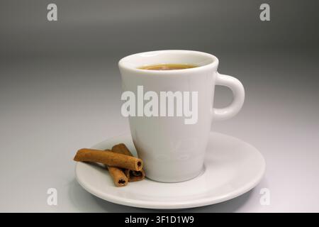 Espresso in una tazza bianca con bastoncino di cannella Foto Stock